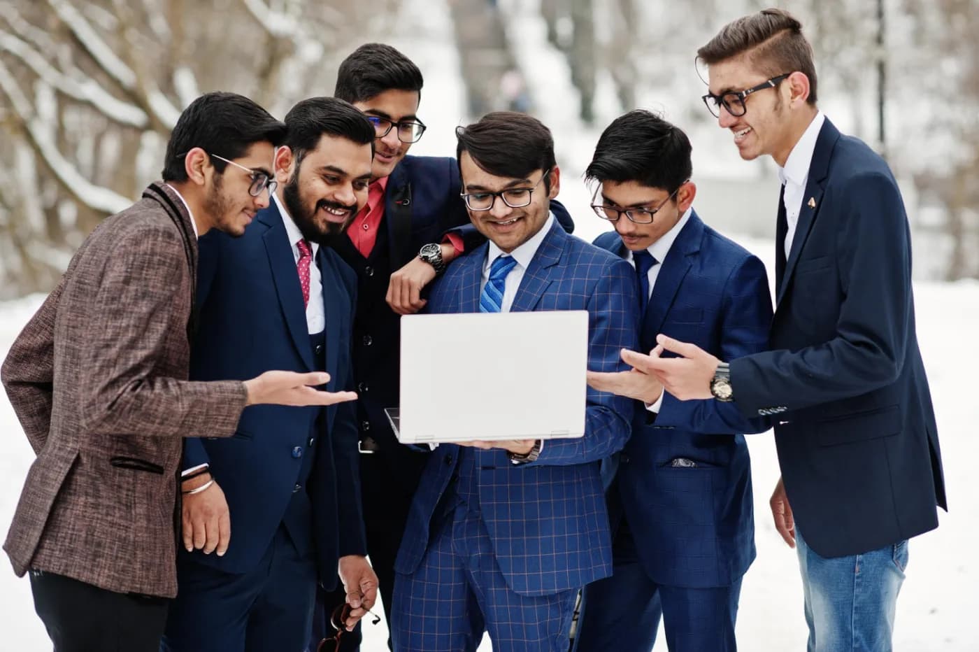 Students in formal wear gathered around a laptop, reading together